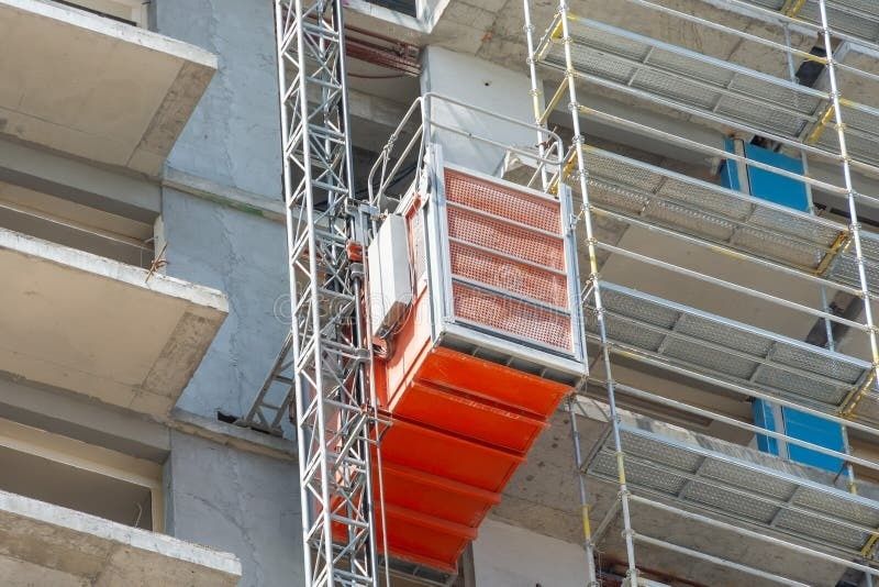 Roter Bauaufzug zwischen Gerüst und Rohbau eines innerstädtischen Gebäudes